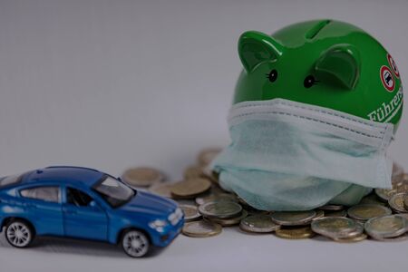 A blue car and a green piggy bank with a face mask.の写真素材