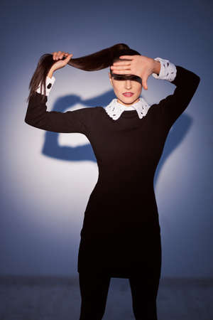 Woman in black dress looking at camera. Studio shot, posing.