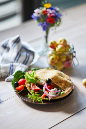 Close up of flatbread pita with vegetables, cucumber, tomato, red pepper at the wooden table.の写真素材