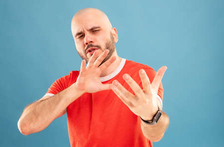 A bald middle-aged man with a beard in a red T-shirt on a blue background stands with his arms shows how simple everything is. Isolatedの写真素材