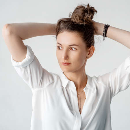 Beautiful girl in white clothes sits on the floor on a white background.の写真素材