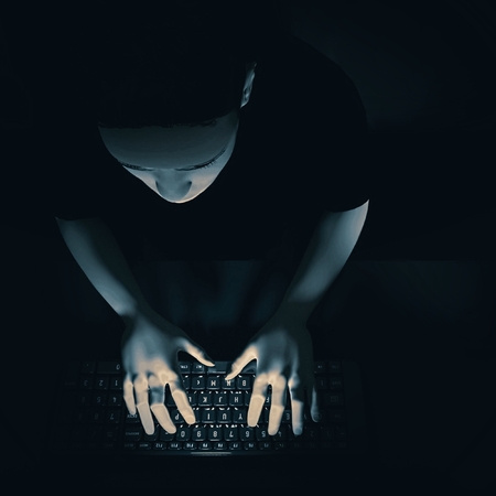 Young man sitting at a computer in the dark. 3d renderの写真素材