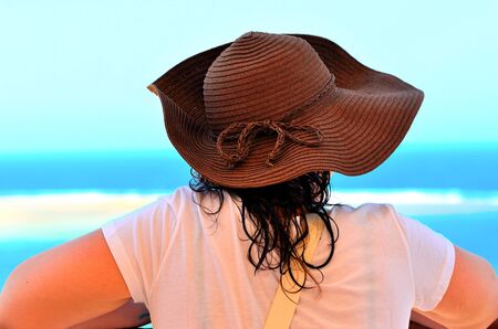 young woman with hat looking at the seaの写真素材
