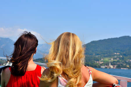 two young women observe the panorama from the lake como italy boatのeditorial素材