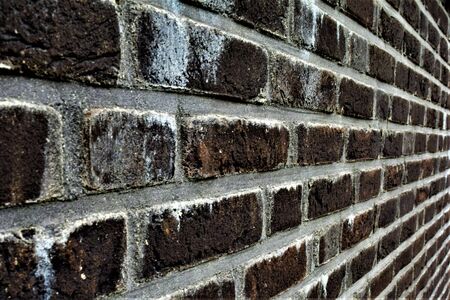 Brown brick wall with white limescale spotsの写真素材