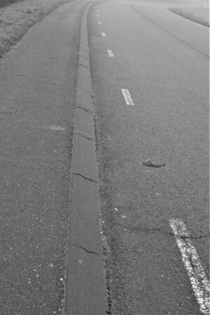 White stripes on the road along curb black and whiteの写真素材