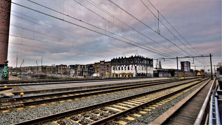 Wide angle cityscape with railway, power lines, historical houses and clouds in the skyの写真素材