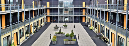 wide angel overview from a courtyard and gallery in an apartment building with yellow doors plants and tilesの写真素材