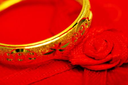 Close up of a golden ring beside the red rose ribbon.の写真素材