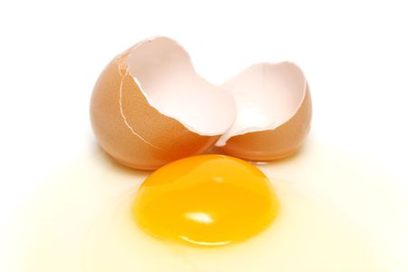 Broken egg with yolk, albumin and eggshell over white background.の写真素材