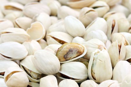 Close up of many salted pistachios with nutshell.