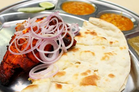 Close up of tandoori chicken and naan bread on steel plate.の写真素材