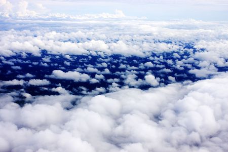 Aerial view of cloudy blue sky from aircraft window.
