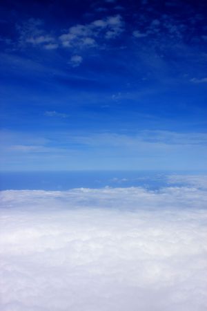 Aerial view of cloudy blue sky from aircraft window.