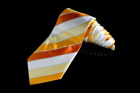An orange necktie with stripes on black background.の写真素材