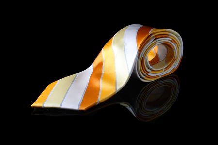 An orange necktie with stripes on black background.の写真素材