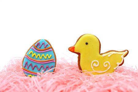 Close up of easter egg and duck cookies on pink ribbons over white background.の写真素材