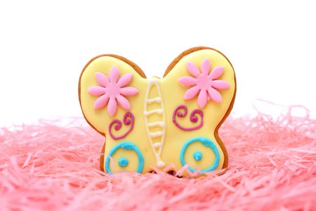 Close up of butterfly cookie on pink ribbons over white background.