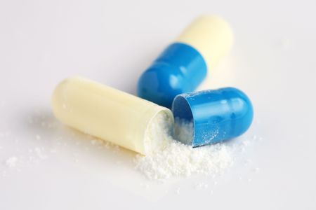 Close up of pill peeled into half with powder isolated on white background