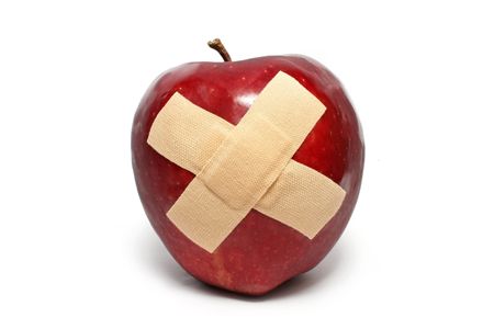An injured red apple with plaster on it isolated over white background.の写真素材