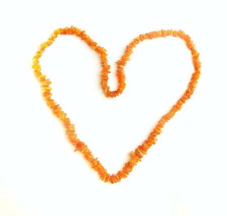 amber beads in the shape of a heart on a white backgroundの写真素材