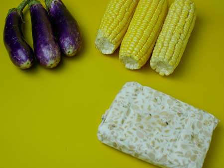 corn, eggplant and tempeh for healthy food concept isolated on yellow background. vegetarian foodの写真素材