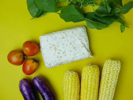 the concept of healthy food consists of eggplant, spinach, tomatoes, and corn. vegetarian food. isolated on a yellow backgroundの写真素材