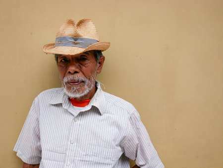 asian old man with white mustache and beard, casual pose with hat. portrait of old man from village in simple styleの写真素材