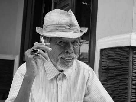 black and white potrait of asian old man smoking with a happy face. portrait of an old man from rural Indonesiaの写真素材