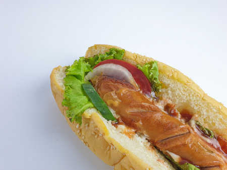 close up of hotdog complete with sauce, lettuce, tomato and cucumber. isolated on a white backgroundの写真素材