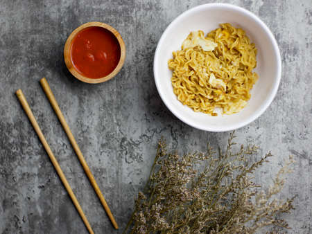 Fried noodles in a white bowl, with sauce in a small bamboo bowlの写真素材