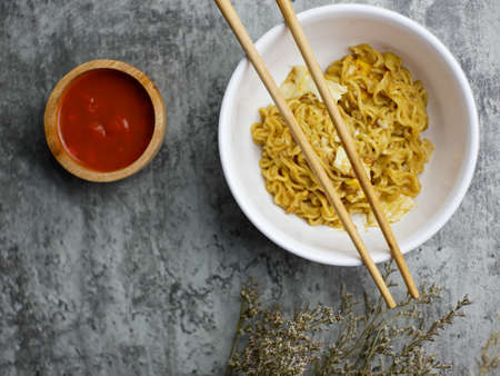 Fried noodles in a white bowl, with sauce in a small bamboo bowlの写真素材