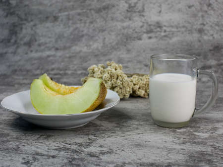a glass of milk, and a sliced melon on a plate. for the concept of healthy food