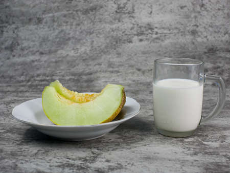 a glass of milk, and a sliced melon on a plate. for the concept of healthy foodの写真素材