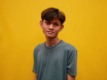 portrait of young asian man with flat expression. with a yellow studio background.の写真素材