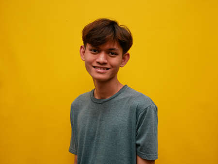 portrait of asian man with happy expression. with a yellow studio background.の写真素材