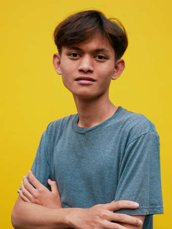 Portrait of smiling young Asian man with folded handsの写真素材