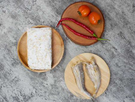 salted fish, raw tempeh and vegetables on a wooden cutting board. kitchen food conceptの写真素材