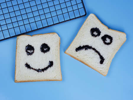 toasted bread with smiley and sad emoticons, for the concept of happiness and sadnessの写真素材