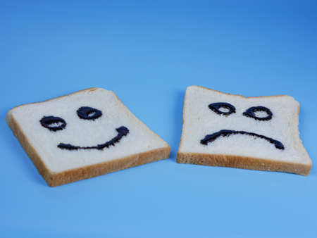 toasted bread with smiley and sad emoticons, for the concept of happiness and sadnessの写真素材