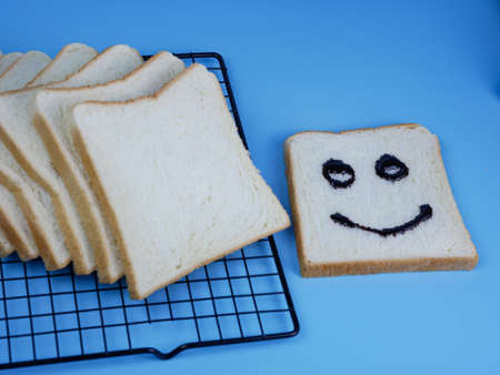 white bread with smiley emoticon on blue pastel backgroundの写真素材