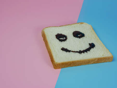 white bread with smiley emoticon on blue and pink pastel backgroundの写真素材