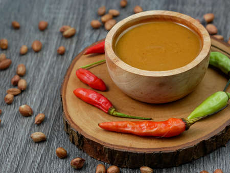 peanut sauce in a small wooden bowl on a gray wood texture background.の写真素材
