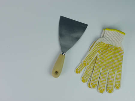 Scrapper or putty knife and work gloves isolated on white background.の写真素材