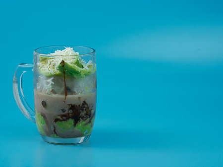 cold drink filled with avocado and chocolate milk on blue background.