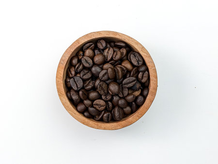 top view of coffee beans in wooden bowl isolated on whiteの写真素材