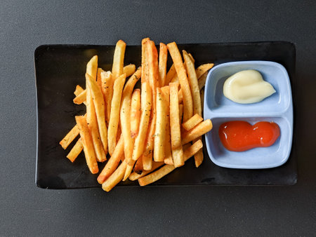 french fries with sauce and mayonnaise on black background. top view