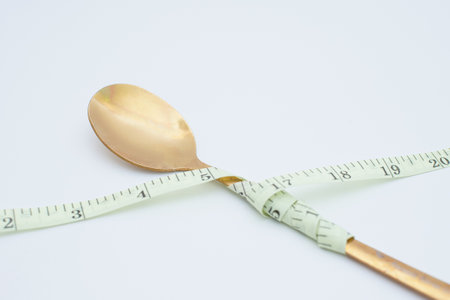 spoon wrapped around measuring tape. diet concept for a healthy lifestyle