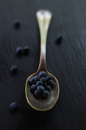 Close up of a spoon filled with wild juniper berries (Juniperus Communis)の写真素材