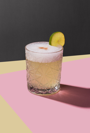 Pisco Sour, IBA cocktail with Pisco, lime or lemon juice, egg white, and angostura. Dark background, pop contemporary style.の写真素材